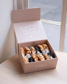 a box filled with donuts sitting on top of a table next to a window