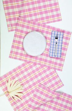 pink and white checkered placemats with silverware on them, next to an empty plate