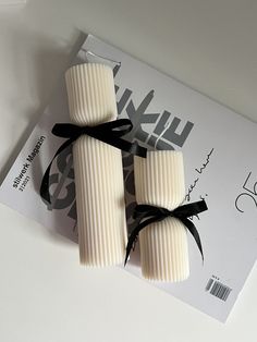 two white soap bars tied with black ribbon on top of a magazine cover and envelope