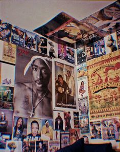 a wall covered in posters and pictures next to a couch