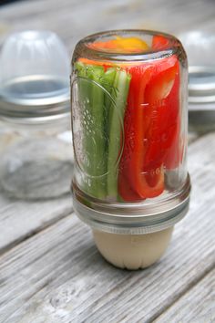 a jar filled with vegetables sitting on top of a wooden table