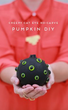 a person holding a black ball with green eyeballs on it and text that reads creepy cat eye no - scarve pumpkin diy