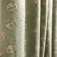 a curtain with flowers on it hanging in front of a window sill next to a wall