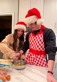 two people in santa hats preparing food together