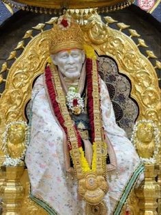 the statue is decorated with gold and red beads on it's head, surrounded by other decorations