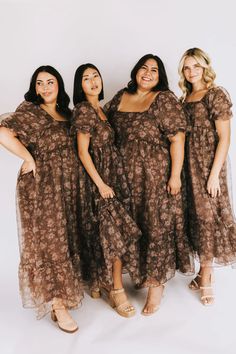 three women in brown dresses standing next to each other with their hands on their hips