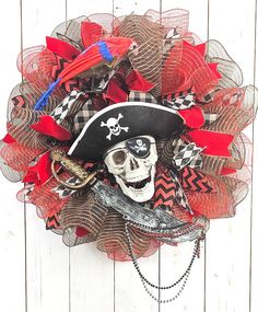 a wreath with a pirate hat and skull on it is hanging on a white wooden wall