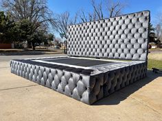 a large bed made out of mattresses on the ground in front of some trees