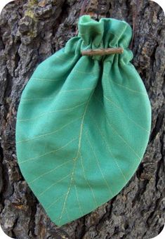 a green bag sitting on the side of a tree trunk with leaves attached to it