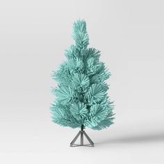 a small blue christmas tree in front of a white background