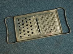 a metal grater sitting on top of a blue cloth covered floor with holes in it