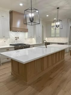 a large kitchen with an island and two pendant lights hanging from it's ceiling