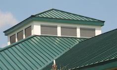 the top of a building with a green metal roof and white trim on it's side