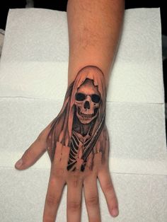 a person's hand with a tattoo on it and a skull in the middle