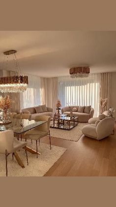 a living room filled with furniture and a chandelier above a glass table surrounded by chairs