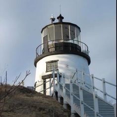 a lighthouse on top of a hill with stairs leading up to the top and below it