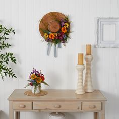 a wooden table topped with vases filled with flowers next to a wall mounted clock