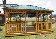 a wooden gazebo sitting on top of a lush green field