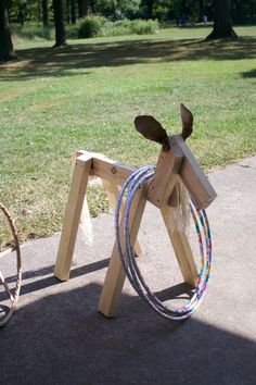 a wooden horse with two ropes attached to it's back and one on the ground