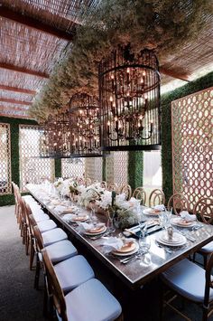 a dining room table is set with place settings and flowers hanging from the rafters