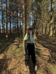 a woman standing in the woods with her hands on her head