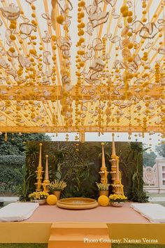 an outdoor ceremony setup with yellow flowers and candles on the table in front of it