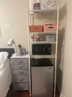 a microwave is on top of a shelf next to a small refrigerator in a bedroom