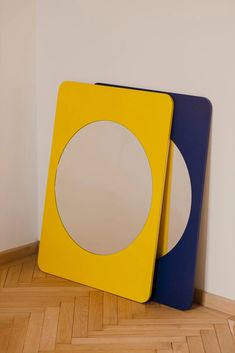 two mirrors sitting on top of a wooden floor next to each other in front of a white wall