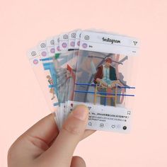 a hand holding four cards with an image of a man sitting on a chair in front of him