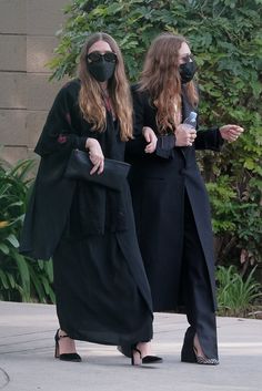 two women wearing masks walking down the street