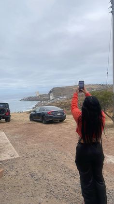 a woman taking a photo of two cars parked on the side of the road with her cell phone