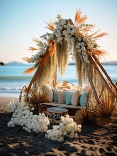 a bed with pillows and flowers on the beach