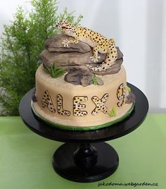 a cake decorated with leopards and the word alex on top is sitting on a black plate