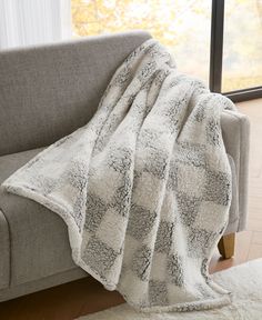 a couch with a blanket on top of it in front of a window and rug