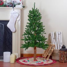 a small christmas tree sitting on top of a wooden floor next to a fire place