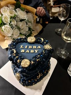 a heart shaped cake sitting on top of a table next to wine glasses and flowers