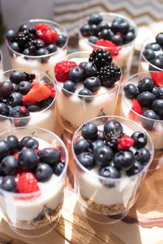 small desserts with berries and yogurt are arranged in individual cups on a tray