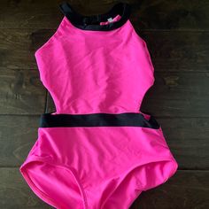 a woman's pink swimsuit laying on top of a wooden floor