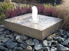 a water fountain surrounded by rocks and plants