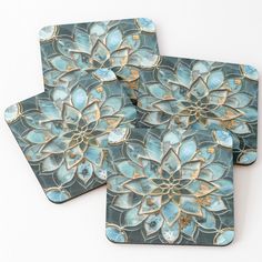 three coasters with blue and gold designs on the top one has a flower design