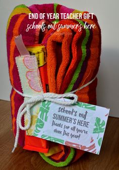 a pile of colorful towels sitting on top of a wooden table next to a sign that says end of year teacher gift