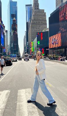 a woman is walking across the street with her hand on her hip while wearing sunglasses