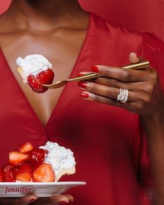 a woman in a red dress holding a plate with strawberries and whipped cream on it