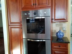 a stainless steel oven in a kitchen with wooden cabinets and granite counter tops on the floor