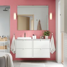 a bathroom with pink and white tiles on the walls, two sinks and a large mirror