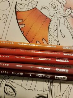 three pencils sitting next to each other on top of a drawing book with an octopus