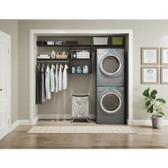 a washer and dryer in a room with clothes hanging on the wall behind it