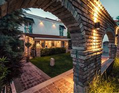 an outside view of a house at night with lights shining on the building and landscaping