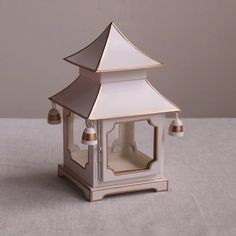 a white and gold lit candle holder with bells on the top, sitting on a table