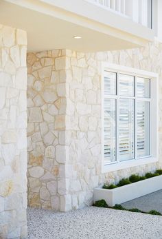 a white window sitting next to a stone building